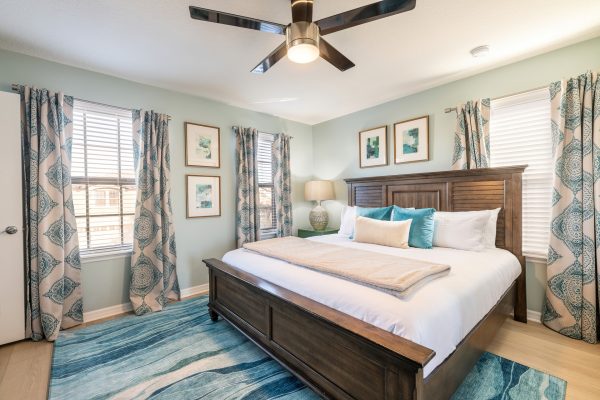 King bedroom with dark wood panel headboard and coastal teal decor at Magic Moments Kissimmee vacation villa